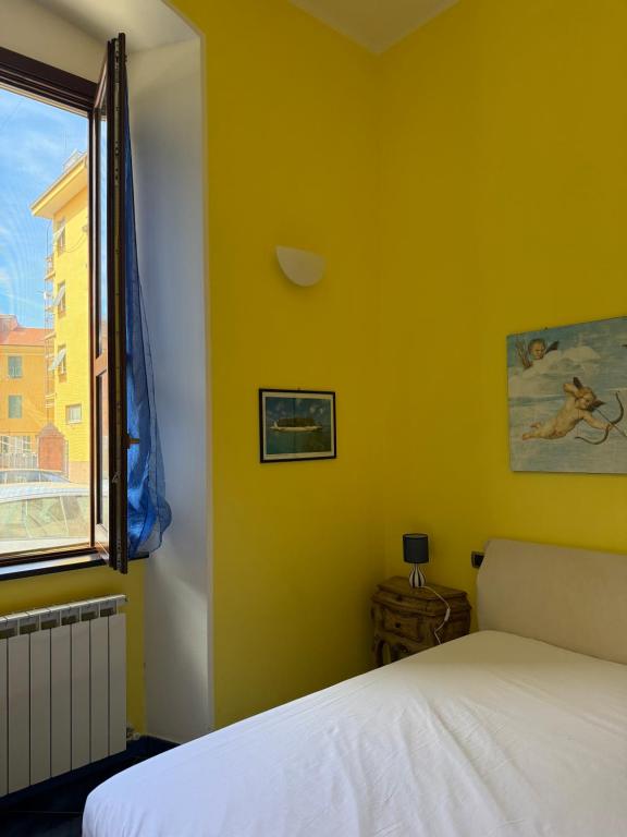 a bedroom with yellow walls and a bed and a window at Casa con Cortile, Barbecue e Parcheggio Privato in Sestri Levante