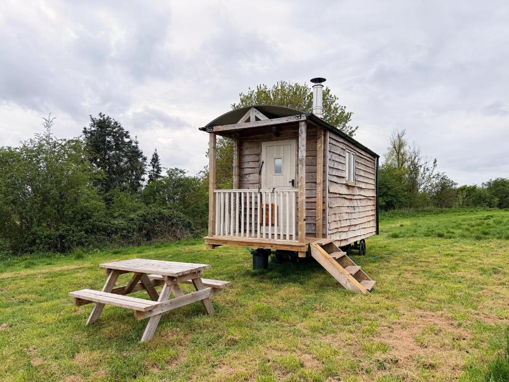 a wooden house with a picnic table and a bench at Herdsman's Hideaway on the Wye in Fawley Station