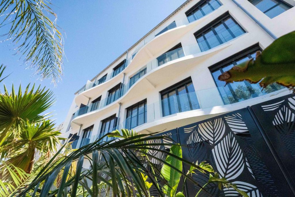 a white building with palm trees in front of it at Eden Islands Marseille Prado in Marseille