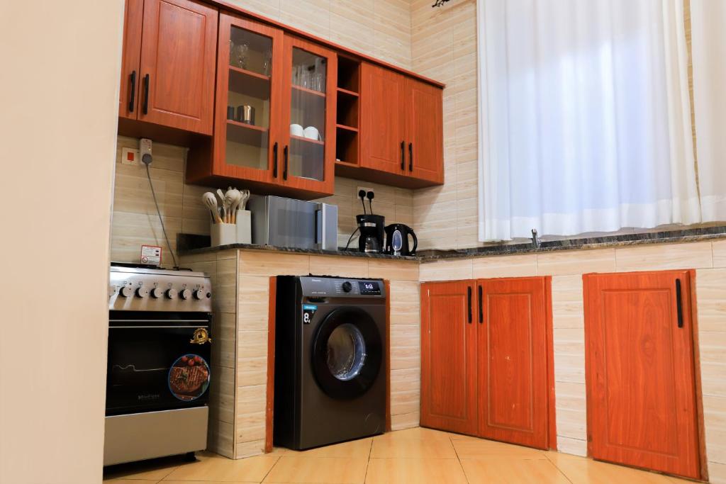 a kitchen with a washing machine and wooden cabinets at Kingram Apartments in Entebbe