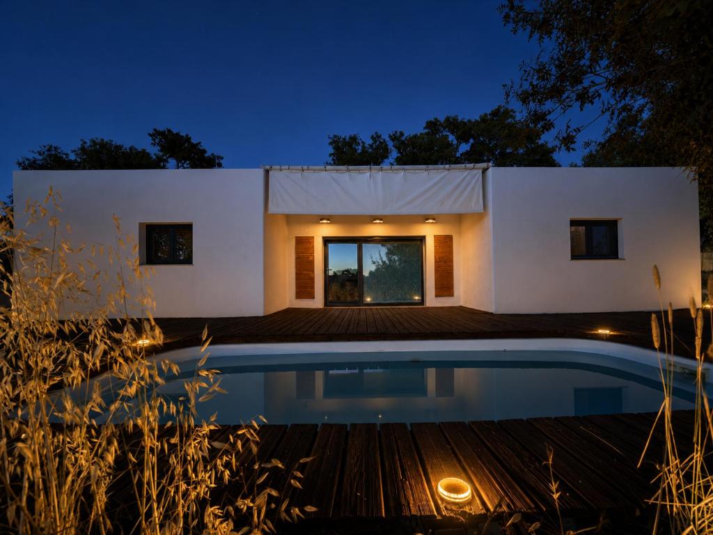 a house with a swimming pool at night at Taipa 2 - Casas de Campo do Junqueirinho in Bicos
