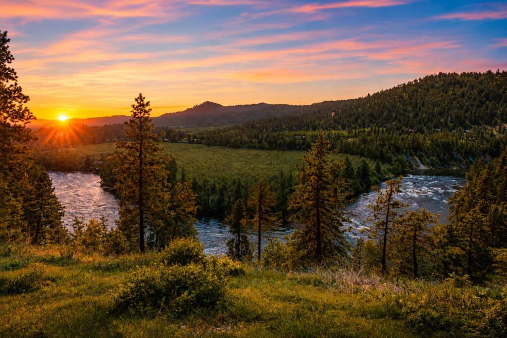 a sunset over a river in a field with trees at River Heights Home cabin in Leavenworth