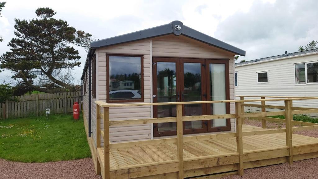 a tiny house with a deck in a yard at Linnet Moselle 5 in Peterhead