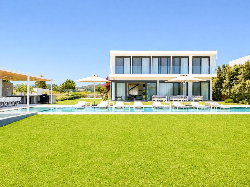 a house with a swimming pool with chairs and umbrellas at Miguel Luxury Beach Front Villa in Fánai