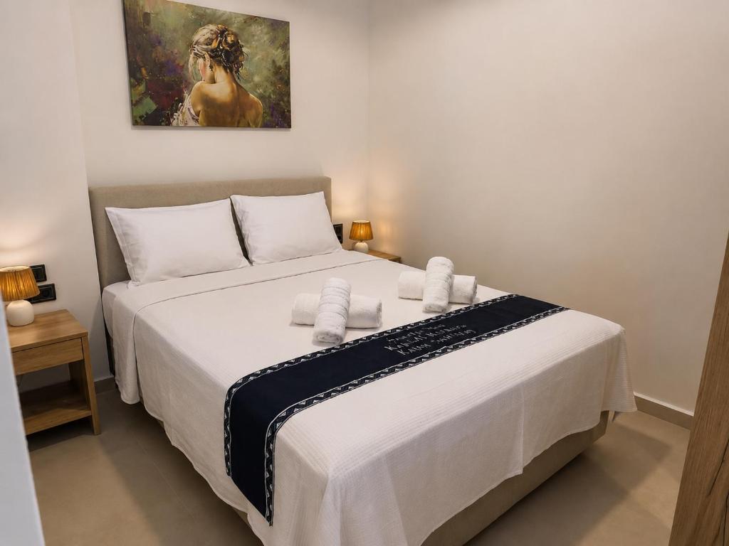 a bedroom with a white bed with a painting on the wall at Seaside Nest in Kythira