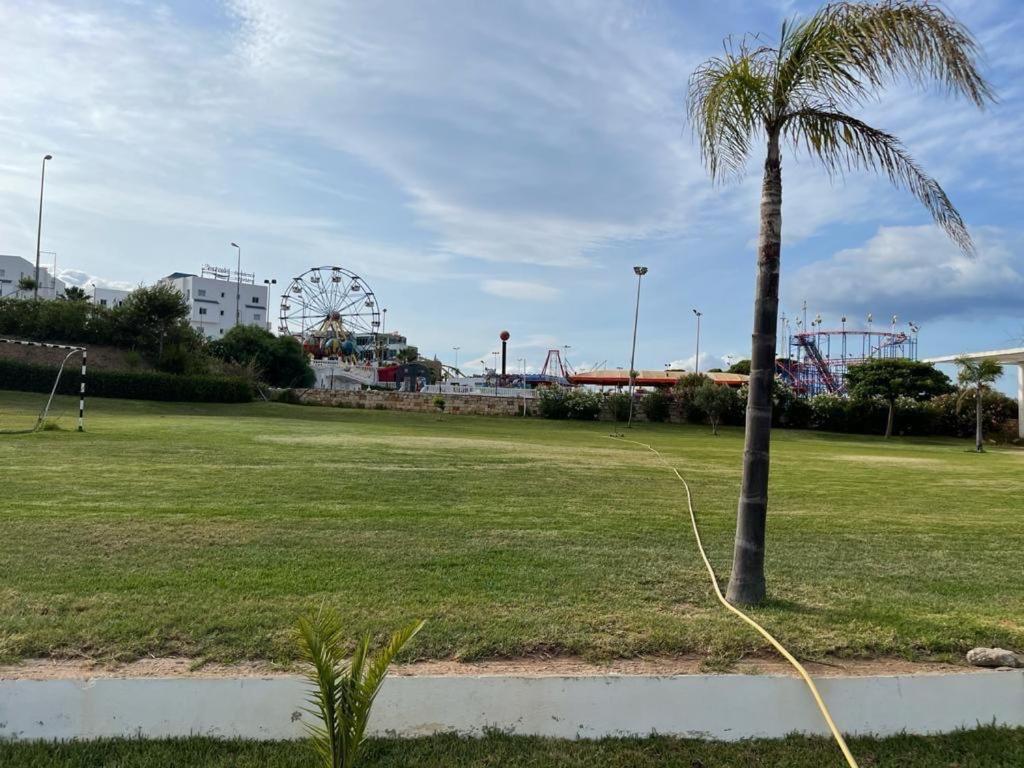 a palm tree in a park with a roller coaster at Apartment inside a apartment complex by the beach with public pool in Marina Smir