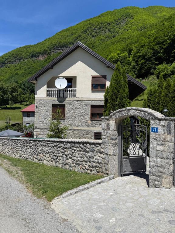 a house with a stone fence and a stone wall at Guest House Vuthaj in Vusanje