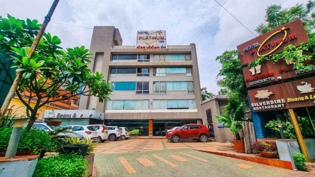 a building with cars parked in a parking lot at Hotel Platinum Inn in Ahmedabad