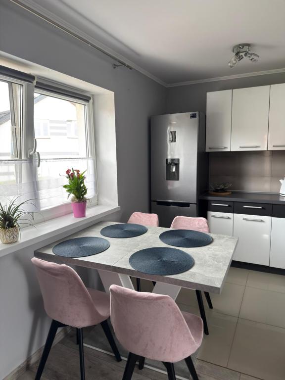 a kitchen with a table and pink chairs in a kitchen at Dom nad jeziorem in Lubkowo