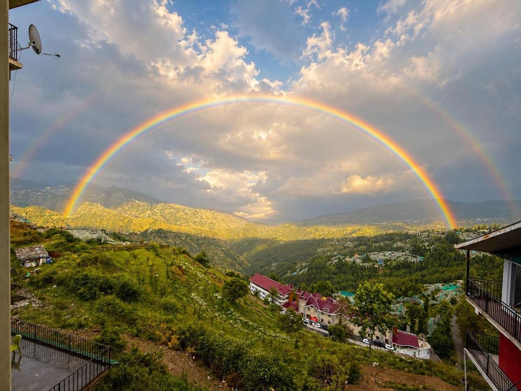 a rainbow in the sky over a city at The Misty Heights l Rooms and Restaurant l Family Groups & Events l Open Air Lawn l Kufri by Exotic Stays in Kūfrī