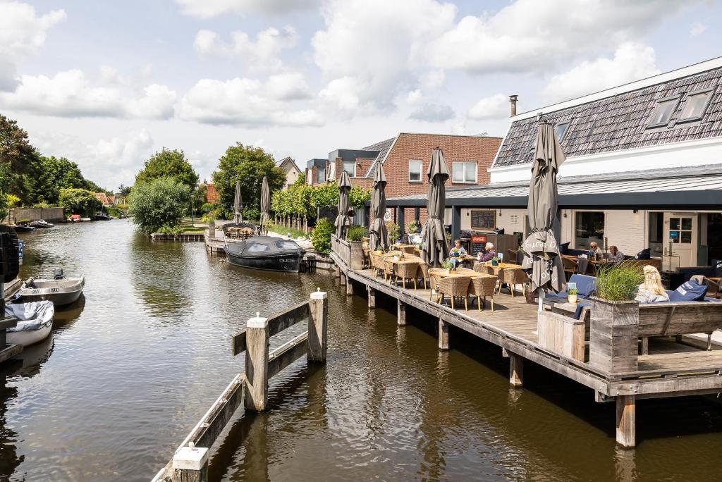 a dock with tables and chairs and boats on a river at De Watersport Heeg in Heeg