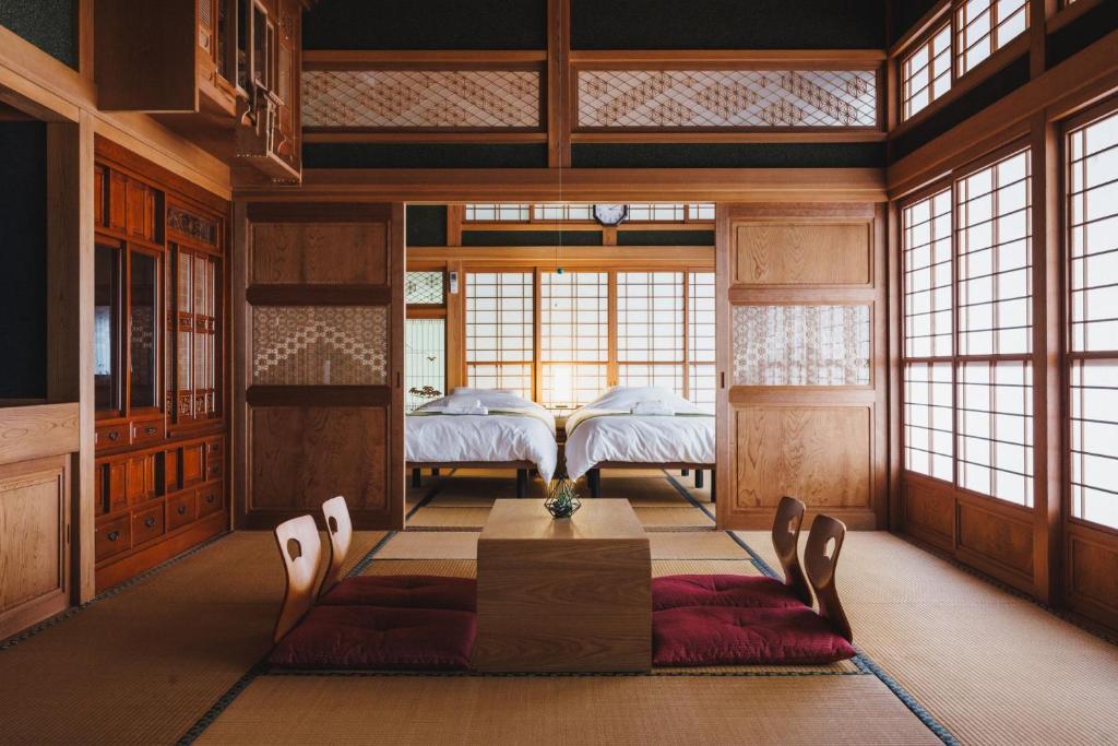 a room with two beds and a table and windows at Irest Village Narita in Narita