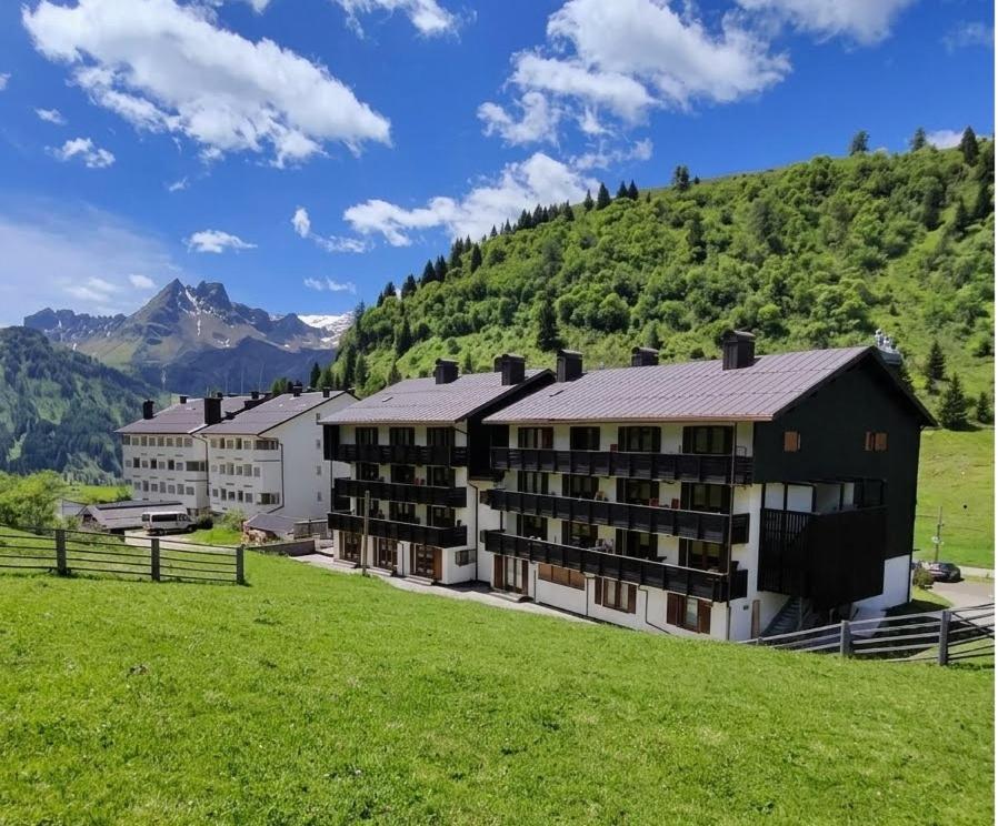 a building on a hill with mountains in the background at Grifone Dolomiti Resort in Arabba