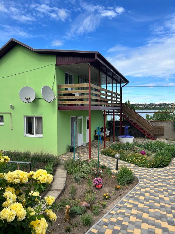 a green house with a balcony and flowers at Зелений двір in Vapnyarka
