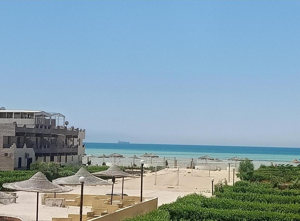 a beach with umbrellas and the ocean at Full board rent in Ras Sedr