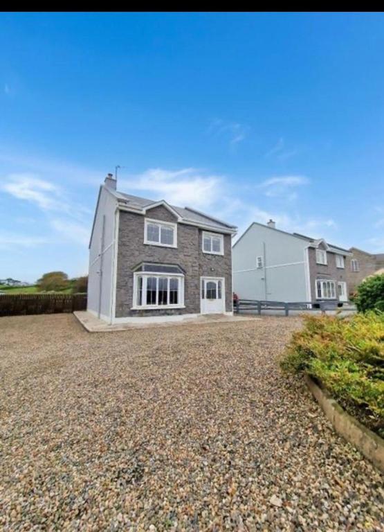 a detached house on a gravel driveway at Atlantic Holiday Home in Milltown Malbay