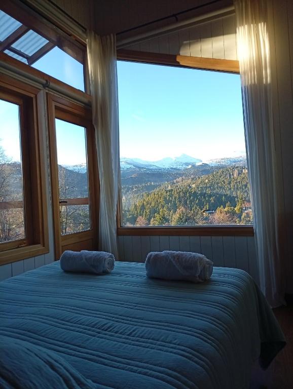 a bedroom with two pillows on a bed with large windows at Cabaña las Frutillas in San Martín de los Andes
