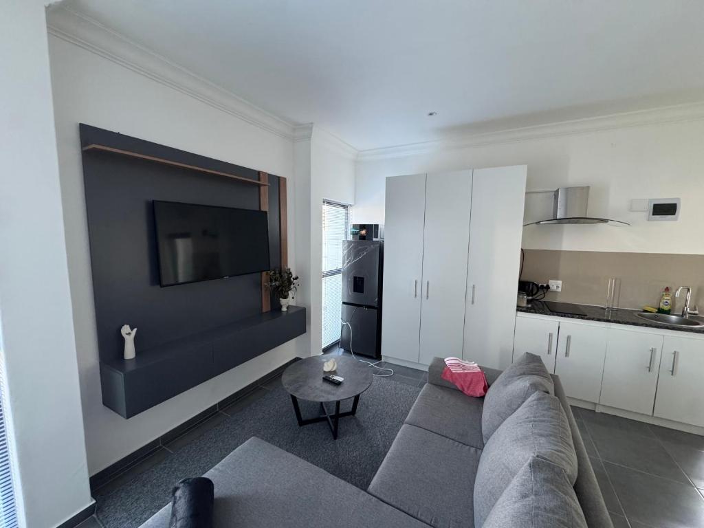a living room with a couch and a kitchen at Muzo Guest Nest in Cape Town