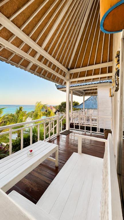 a wooden porch with a bench on a deck with the ocean at Tawe Ocean Blue Villa Lembongan in Nusa Lembongan