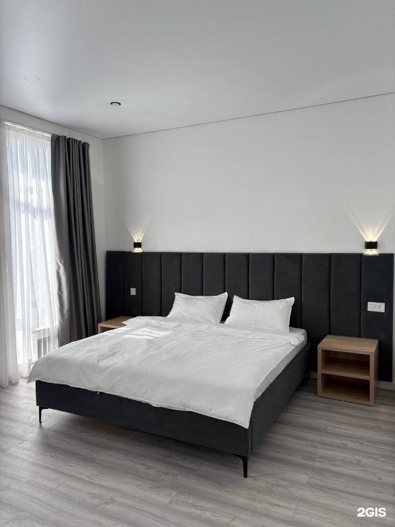 a bedroom with a large bed with a black headboard at TUMAR hotel in Zhezdi