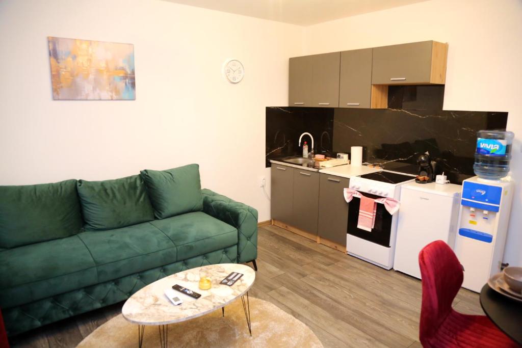 a living room with a green couch and a kitchen at City Apartman 103 in Bosanski Brod