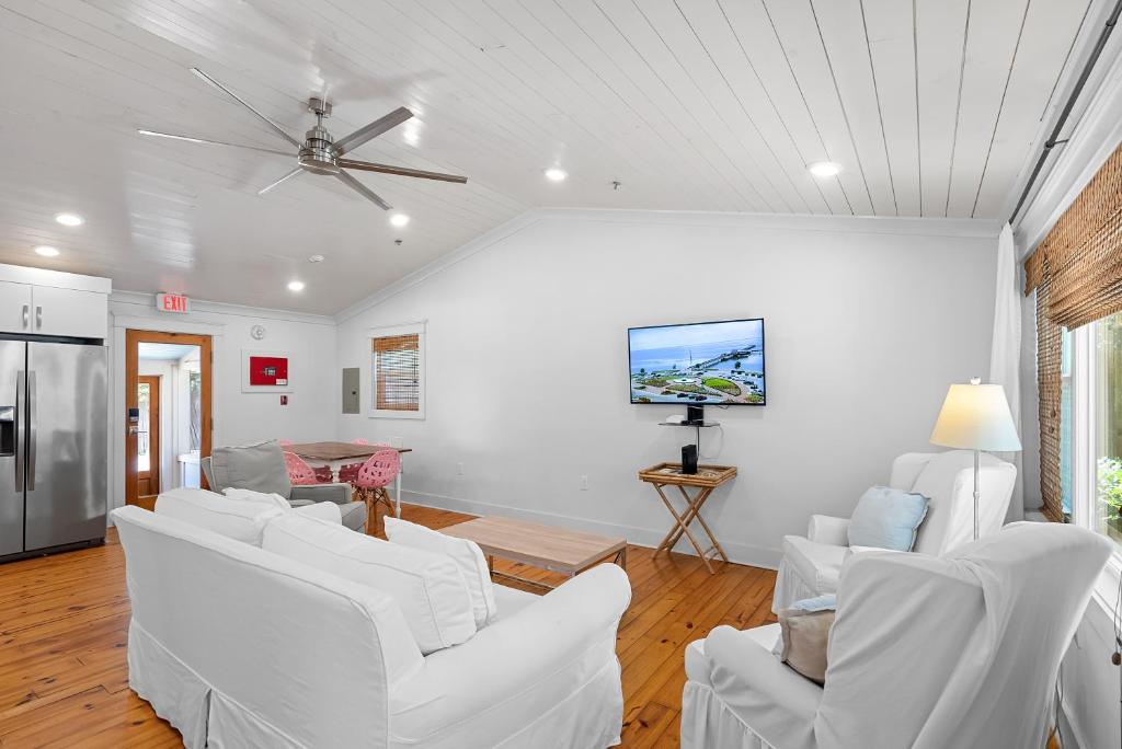 a living room with white couches and a tv at Downtown Fairhope Cottage in Fairhope