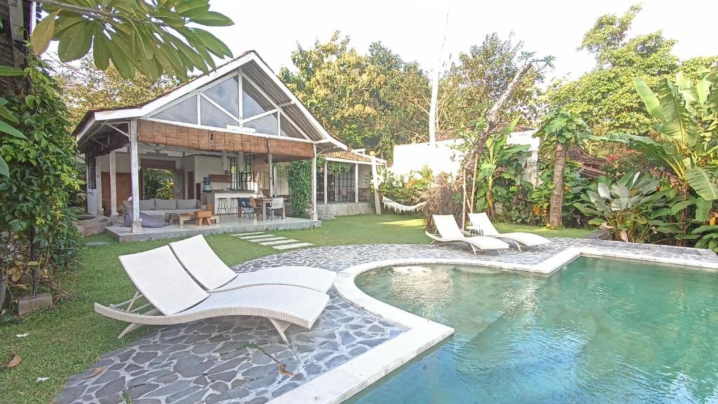 a house with a swimming pool and two white chairs at Sun Moon Star Villas in Jarakan