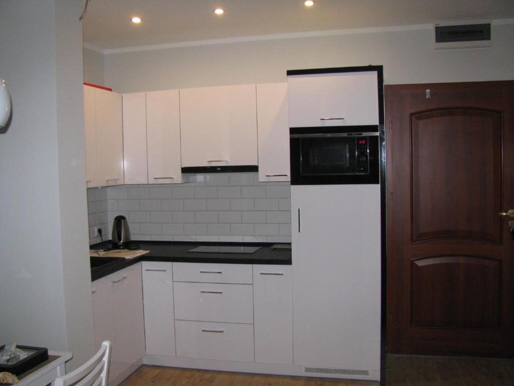 a kitchen with white cabinets and a black microwave at Blue Mare Apartament u Kwiatków in Łukęcin