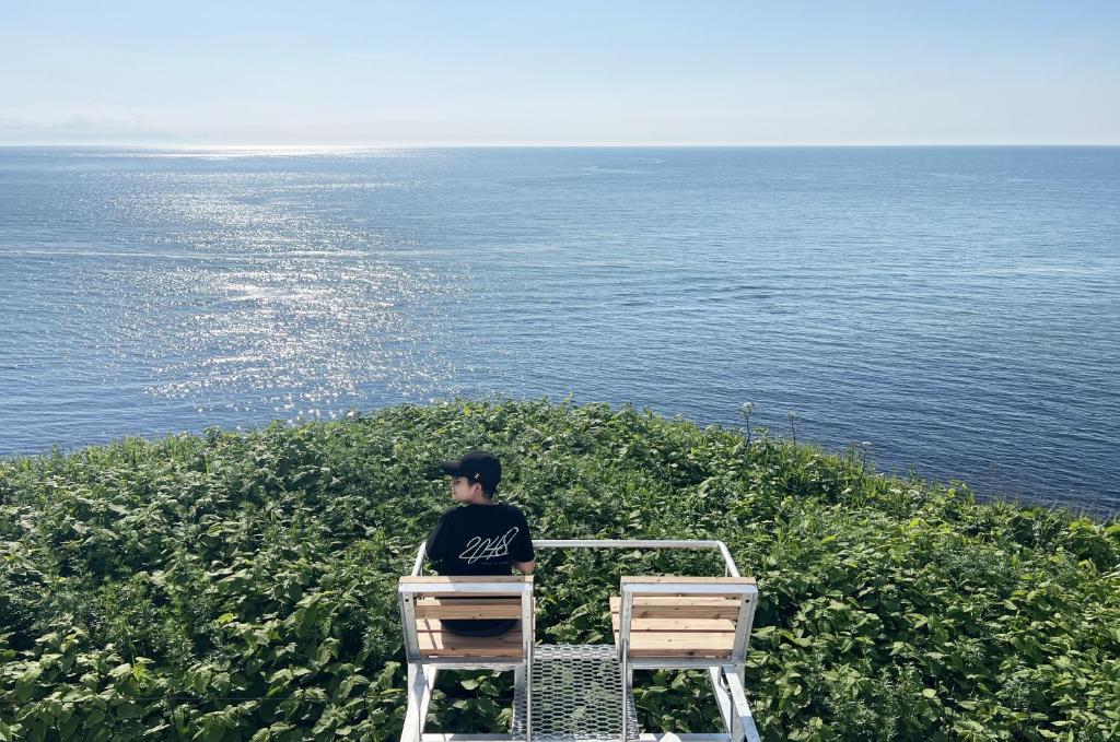 a person sitting in a chair looking at the ocean at Cliff House MORAI 2 in Ishikari