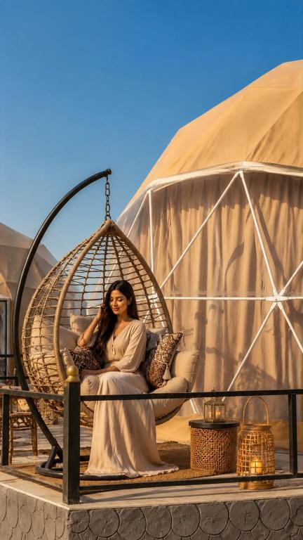 a woman sitting in a swing in a tent at WADI RUM ROTANA BUBBLE lUXURY in Wadi Rum