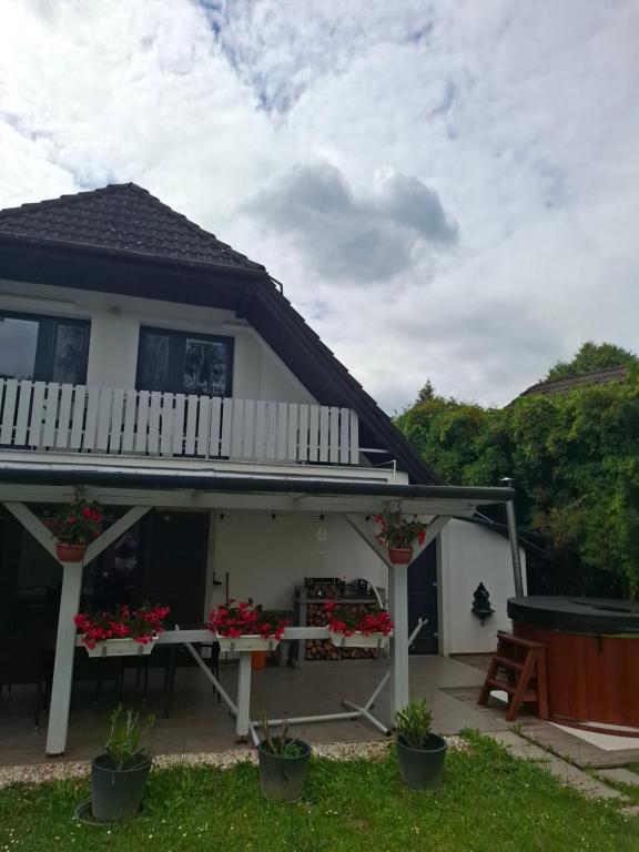 a white house with a porch with flowers on it at Őrségi Csónakház in Hegyhátszentjakab