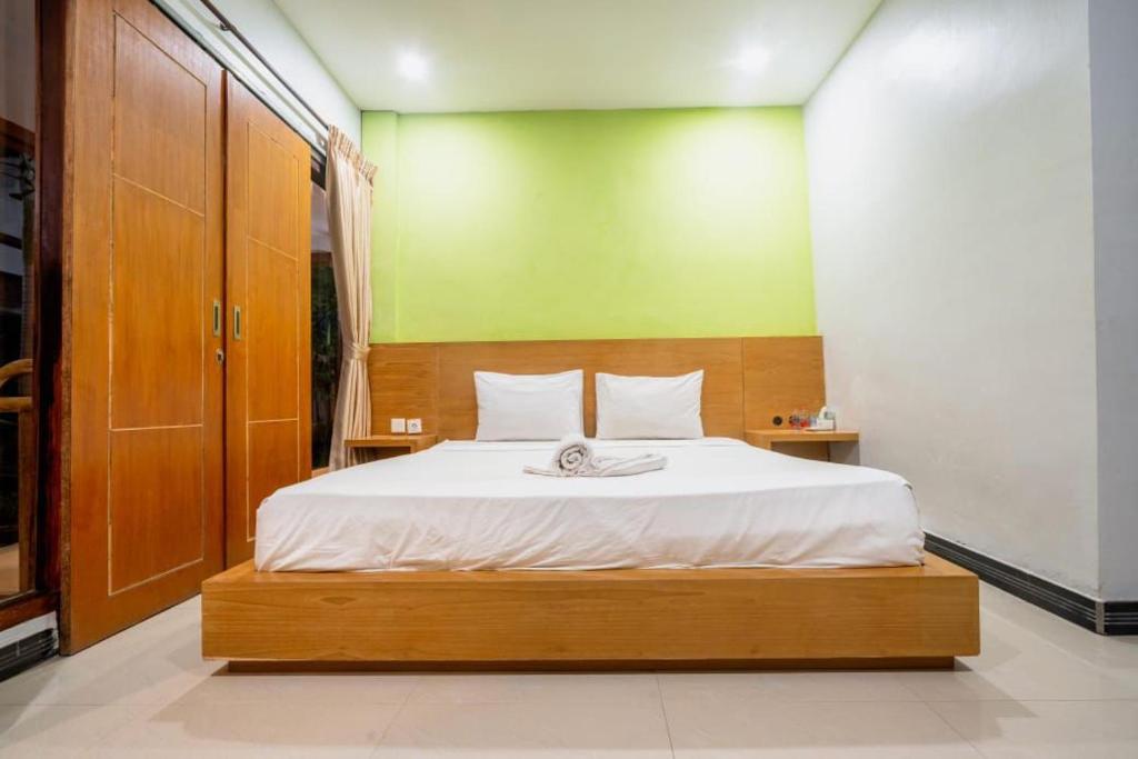 a bedroom with a large bed with a green wall at Melati Hotel central kuta mandalika in Kuta Lombok