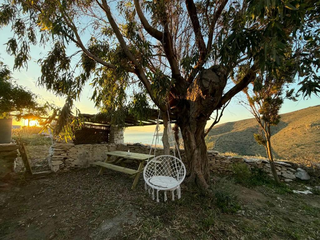 a swinging bench next to a tree with a picnic table at Lefkiani House in Katapola