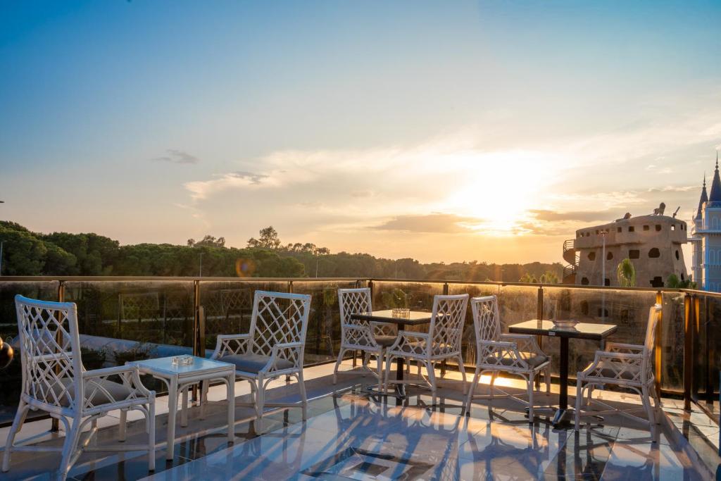 a group of chairs and tables on a balcony with the sunset at Velaris Boutıque Hotel in Belek