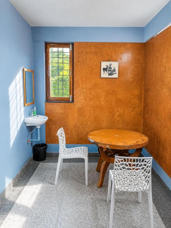 a room with a table and two chairs and a sink at Avora Auroville in Auroville