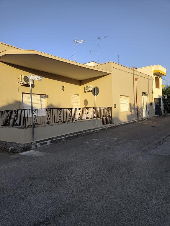 a yellow building with a fence next to a street at B&B Martina in Martignano