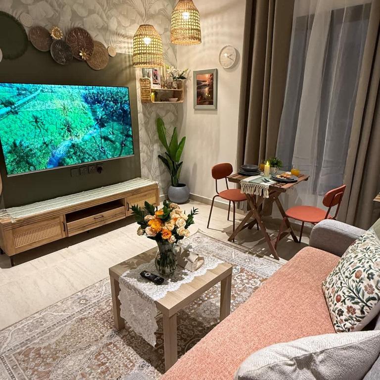 a living room with a large screen tv and a couch at Bali island Home2 in Al Khobar