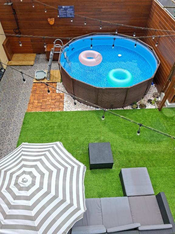 a large pool with an umbrella and grass at Cabo da Vila Guesthouse in Ribeira Grande