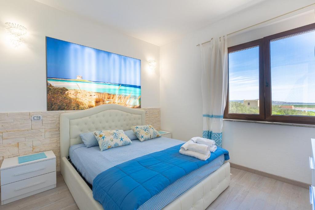 a bedroom with a bed with blue sheets and a large window at Appartamento La Pelosa in Stintino