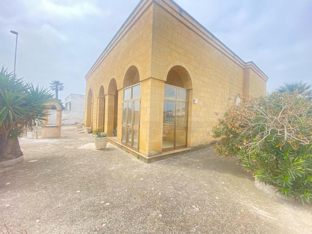 a yellow brick building with large windows and plants at Salento mare in Casalabate