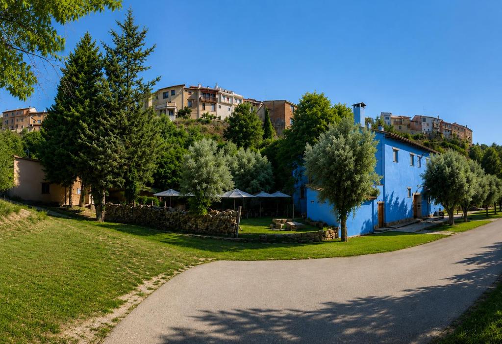 a winding road with a blue building and trees at Complejo Molí de L'Hereu in Ráfales