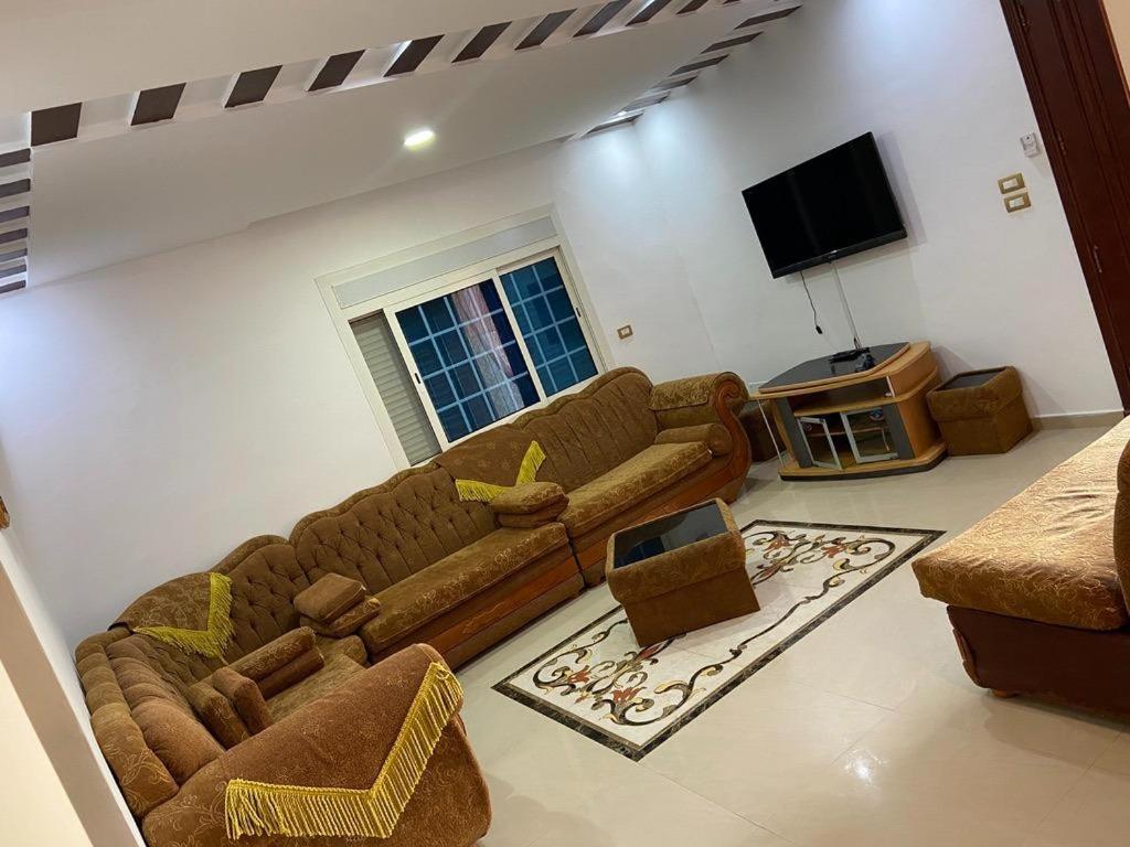 a living room with couches and a flat screen tv at Ain grenz in Kelibia