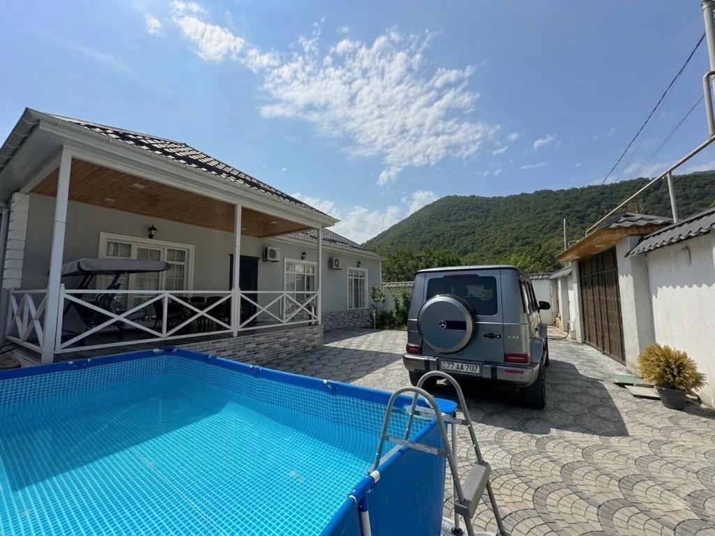 a vehicle parked next to a house with a swimming pool at Qafqaz Hills Villa in Gabala