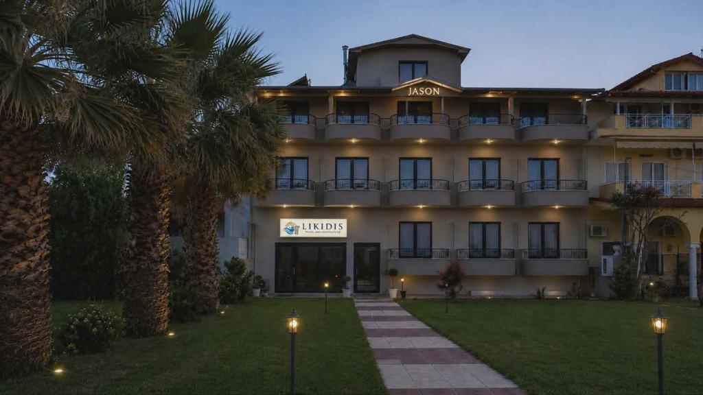 a large hotel with palm trees in front of it at Jason Apartments in Paralia Katerinis