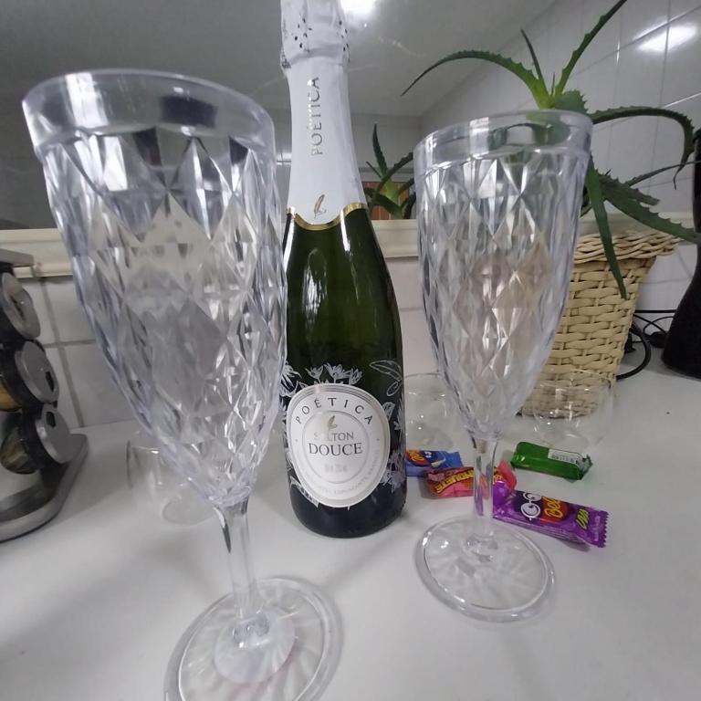 a bottle of champagne and two wine glasses on a counter at Ap Interlagos apoia adversidade in São Paulo