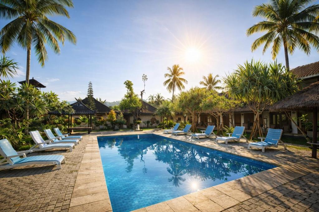 a pool with lounge chairs and palm trees at GGuesthouse in Kuta Lombok
