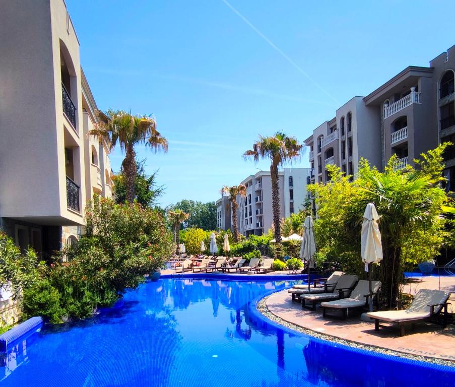 a swimming pool with chairs and umbrellas in a resort at Cascadas, Studio apartment with a pool view in Sunny Beach