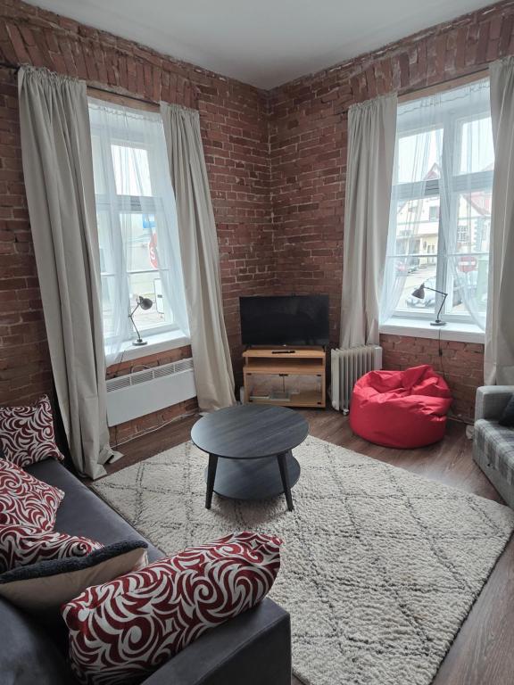 a living room with a couch and a table and windows at Kuninga Apartment in Old Town with Free Parking in Pärnu