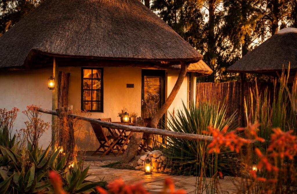 a small house with a thatched roof and a garden at Addo African Home in Addo