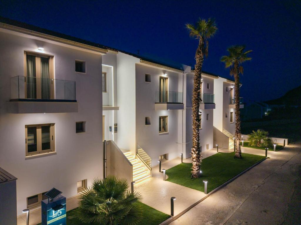 a white building with palm trees in front of it at Latsis Suites in Plytra